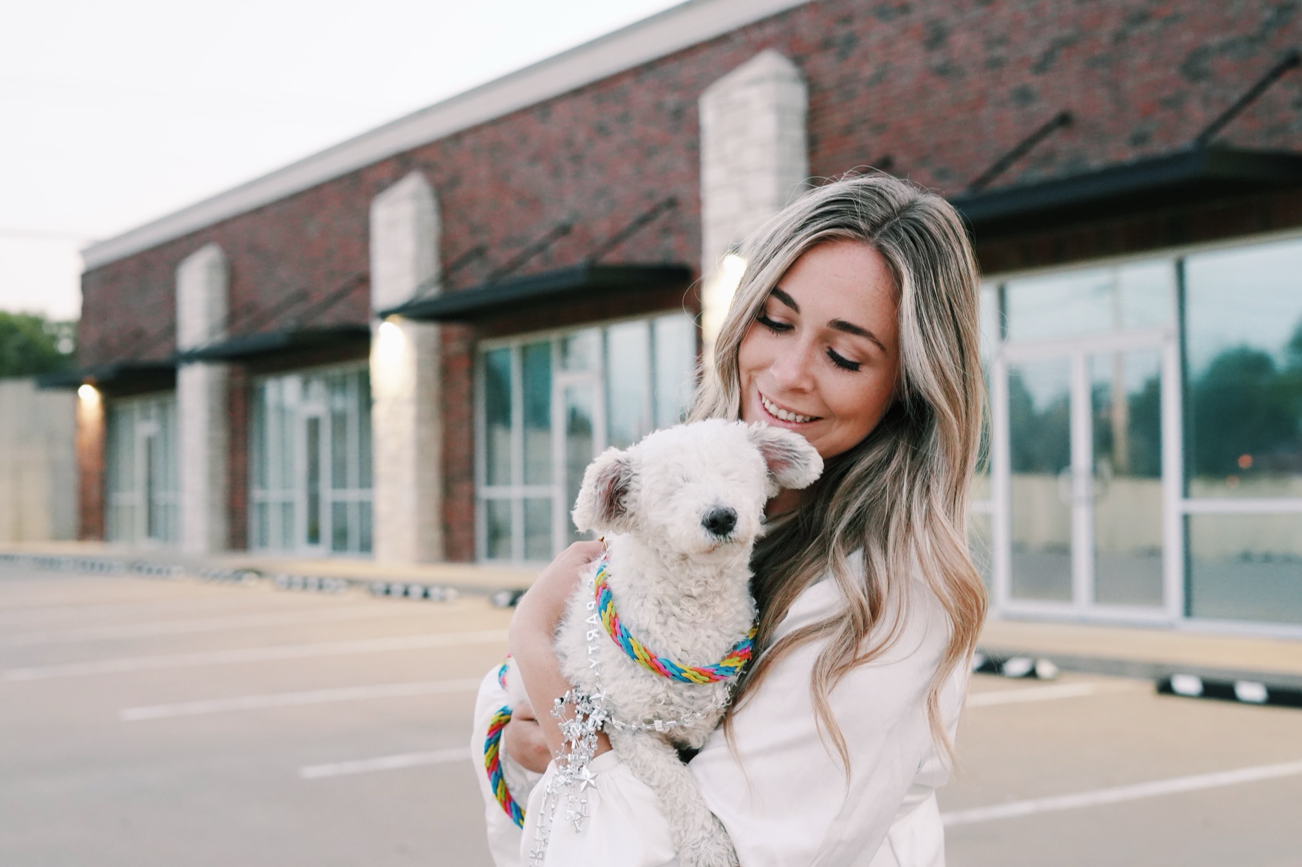 Mia holding Phoebe outside a brick building at golden hour